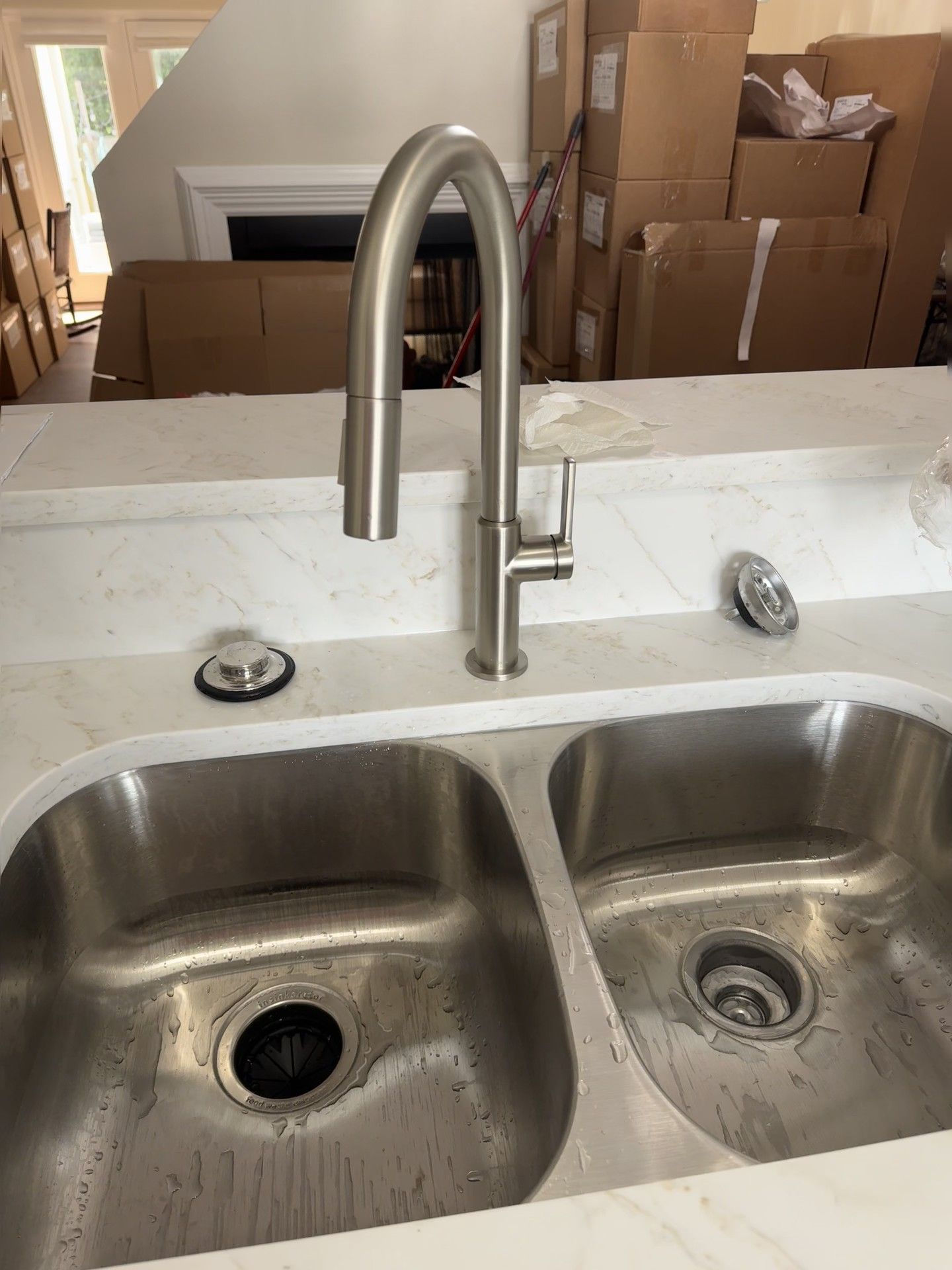 Stainless steel kitchen sink with a pull-down faucet on a white countertop.