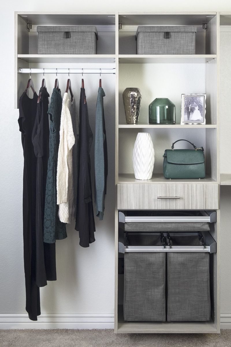 a closet with clothes and a green purse on the shelf .