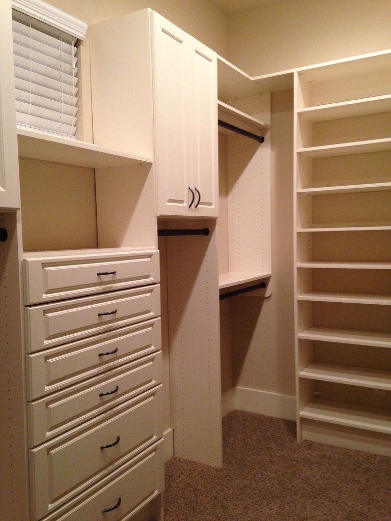 a white walk in closet system with lots of shelves and drawers
