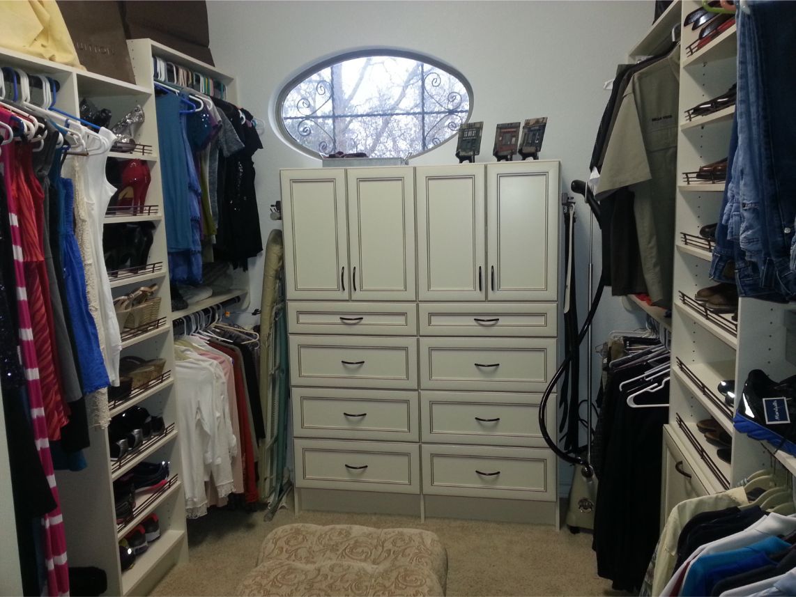 a walk in closet with lots of clothes and a window
