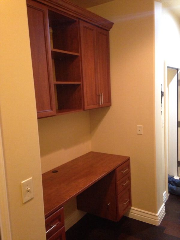 a corner of a room with a wooden desk and cabinets