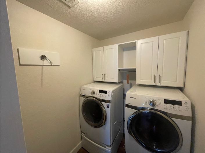 a laundry room with a washer and dryer and white cabinets .