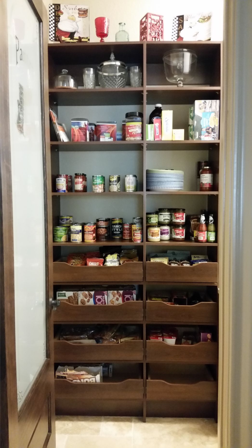 a custom pantry system with lots of food on the shelves and drawers .