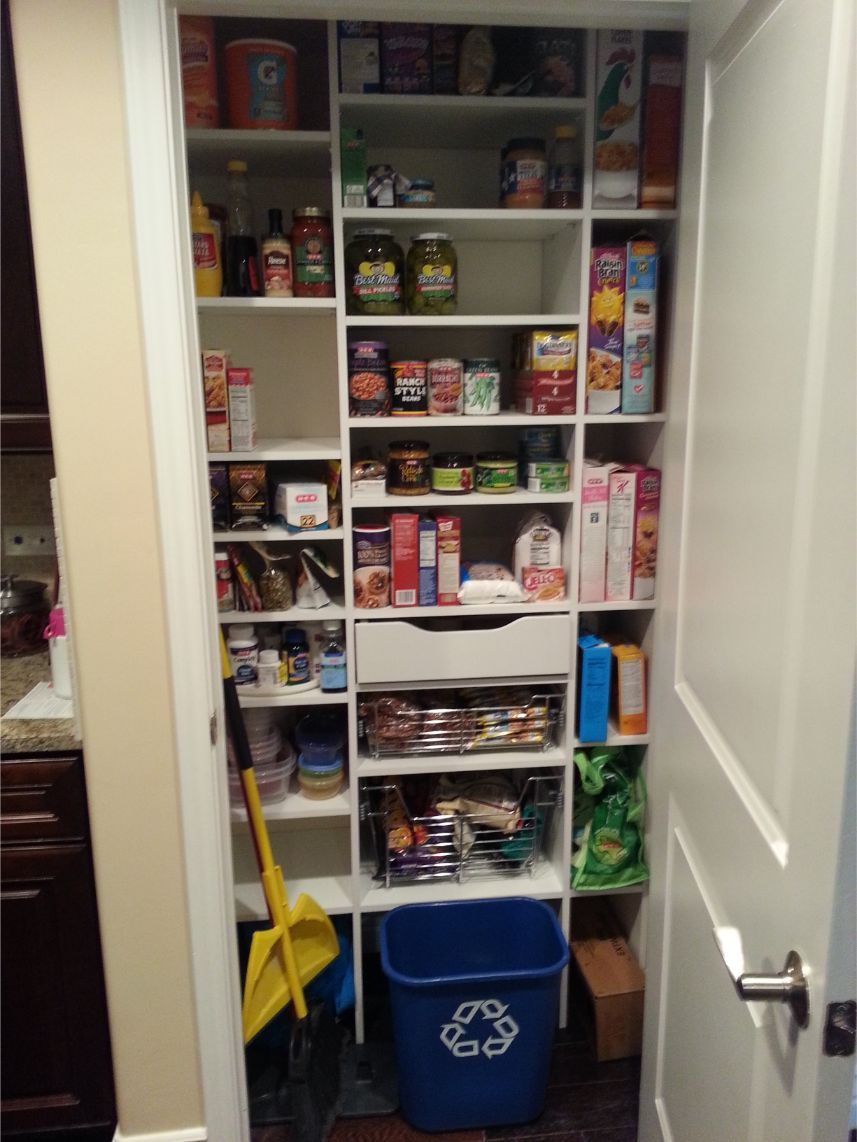 a pantry with a blue recycling bin on the floor