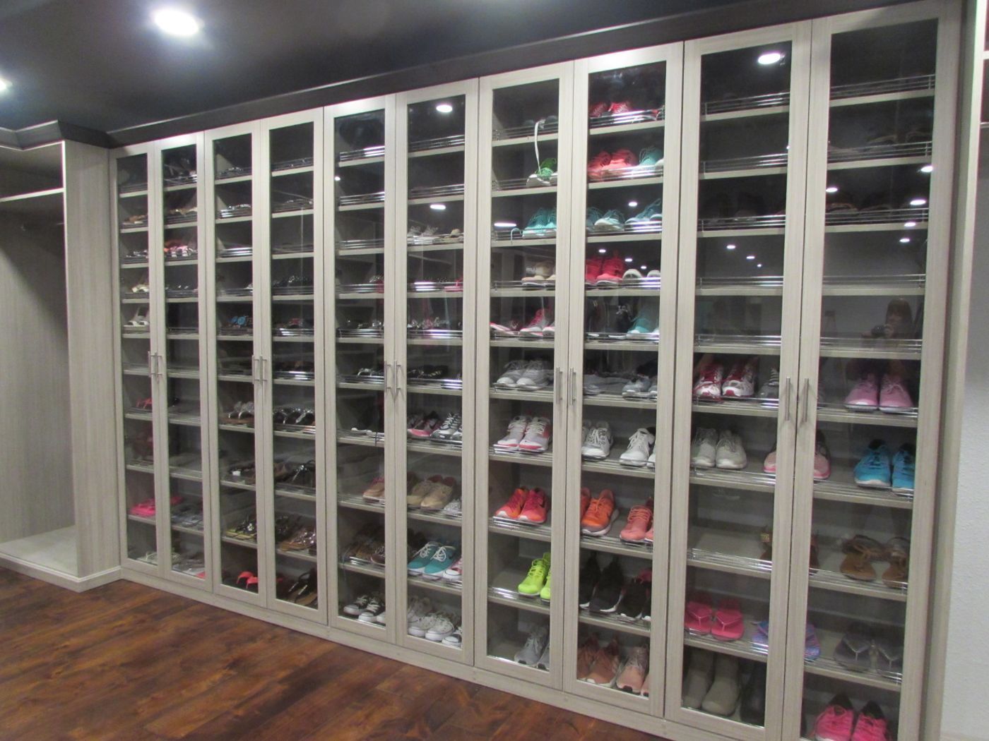 a closet filled with lots of shoes and a lot of glass doors .