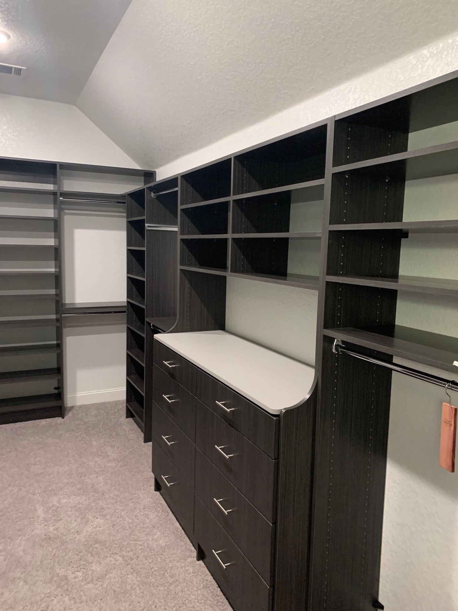 a dark wood walk in closet with lots of shelves and drawers .