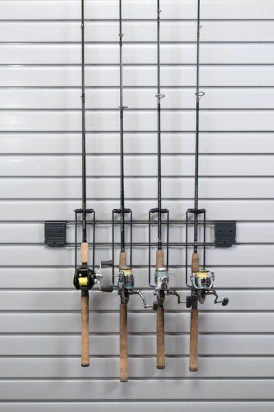 four fishing rods are hanging on a rack on a wall .