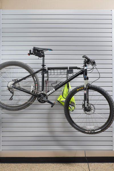 a bicycle is hanging on slatwall in a garage .