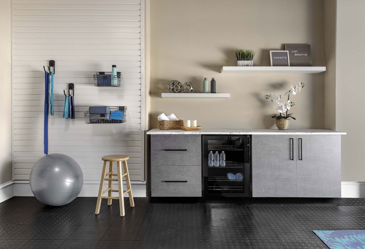 a garage with a stool , a gray exercise ball , and a refrigerator .