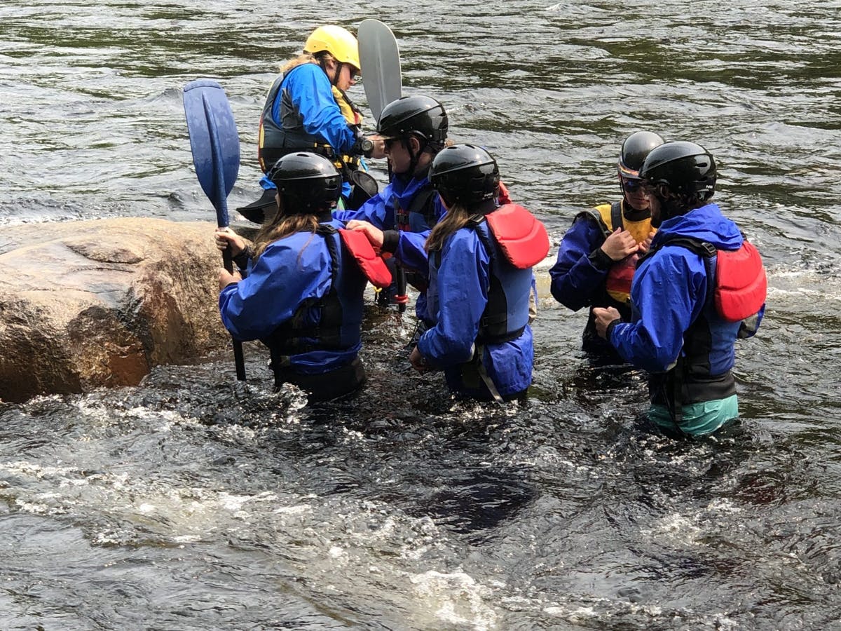 Group of people standing on river holding their paddle