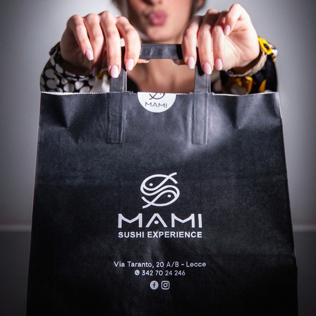 Donna con in mano una borsa della spesa nera con la scritta 