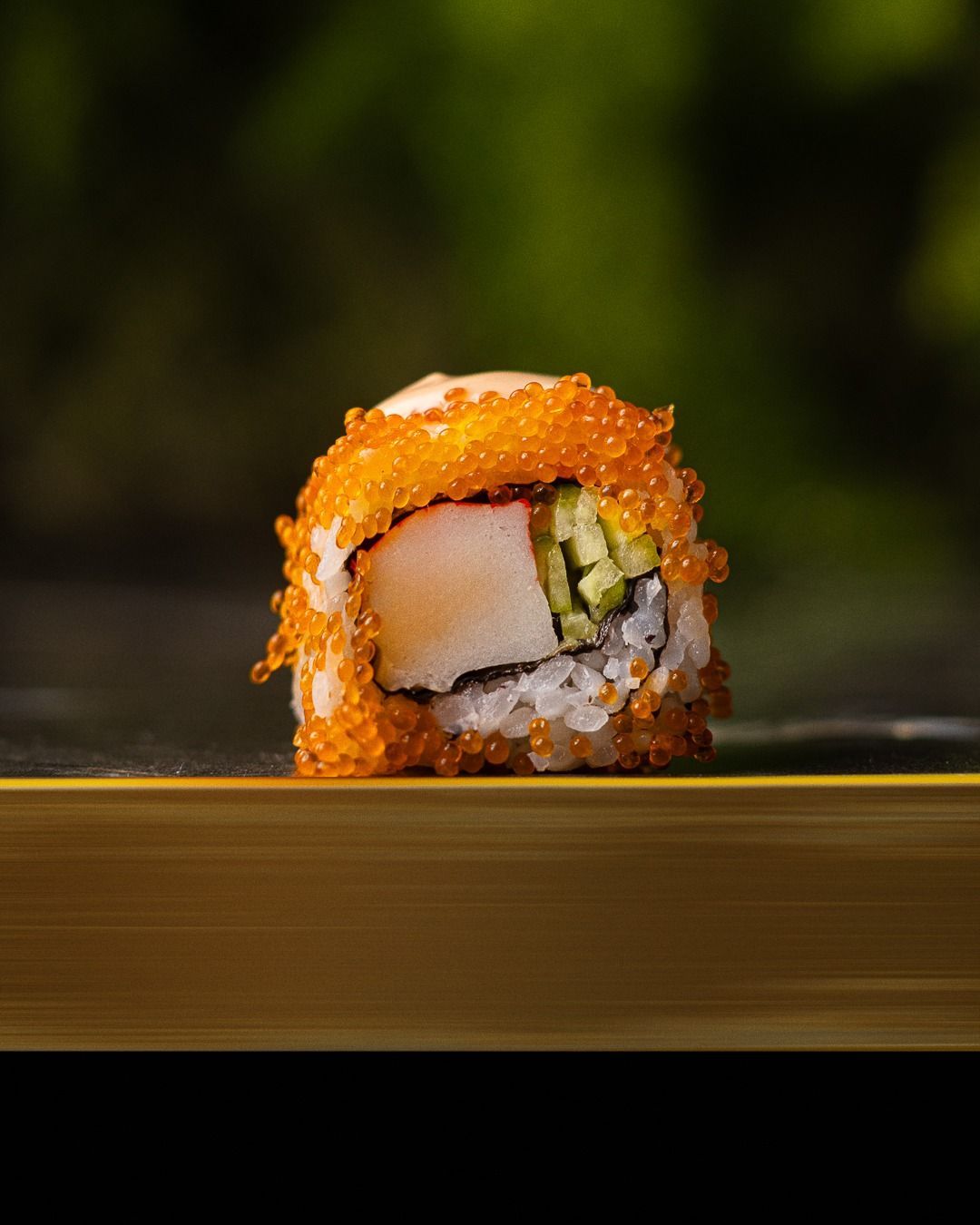 Rotolo di sushi con uova d'arancia, granchio, cetriolo e riso bianco.