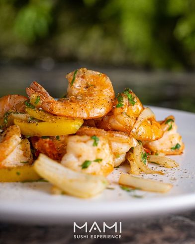Gamberi cotti con spicchi di limone, guarnito con erbe aromatiche su un piatto bianco.