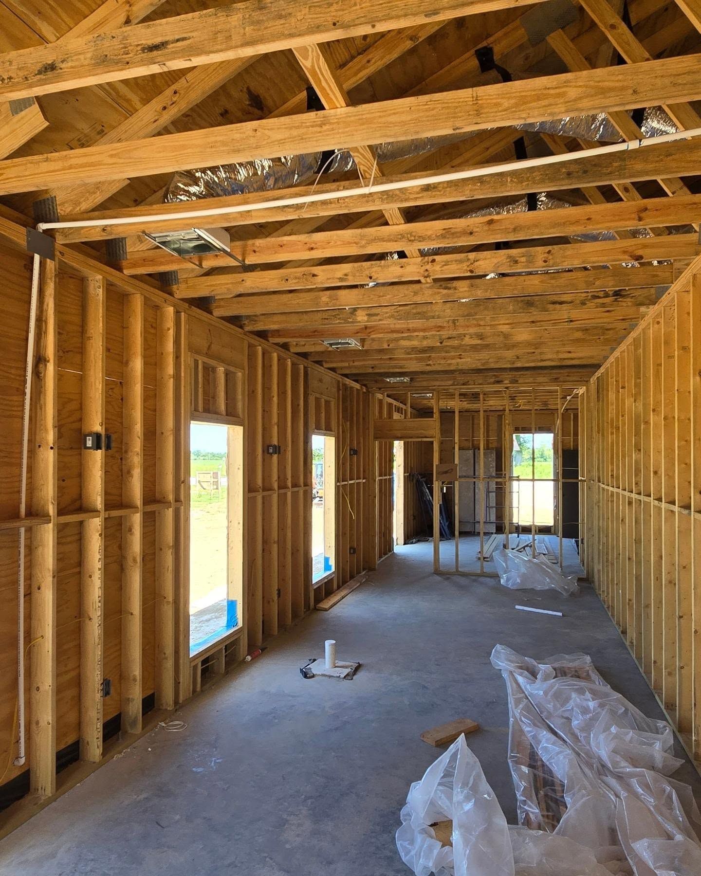 Interior view of a building under construction, showing wooden frames, windows, and exposed ceiling beams.
