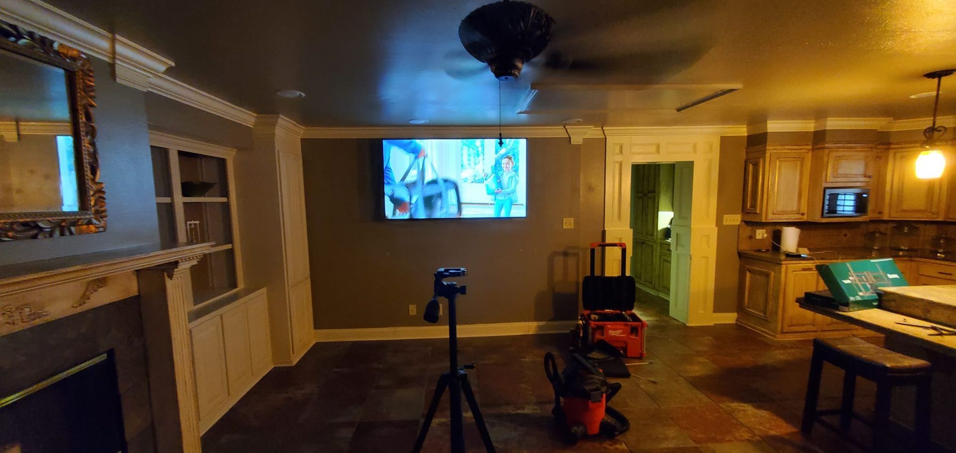 A living room with a TV, kitchen, and tools. The room is dimly lit.