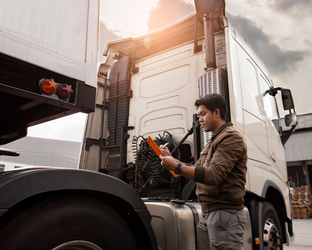 A Man is Standing Next to a Semi Truck Writing on a Clipboard — Hive Mobile Roadworthy in Pimpama, QLD