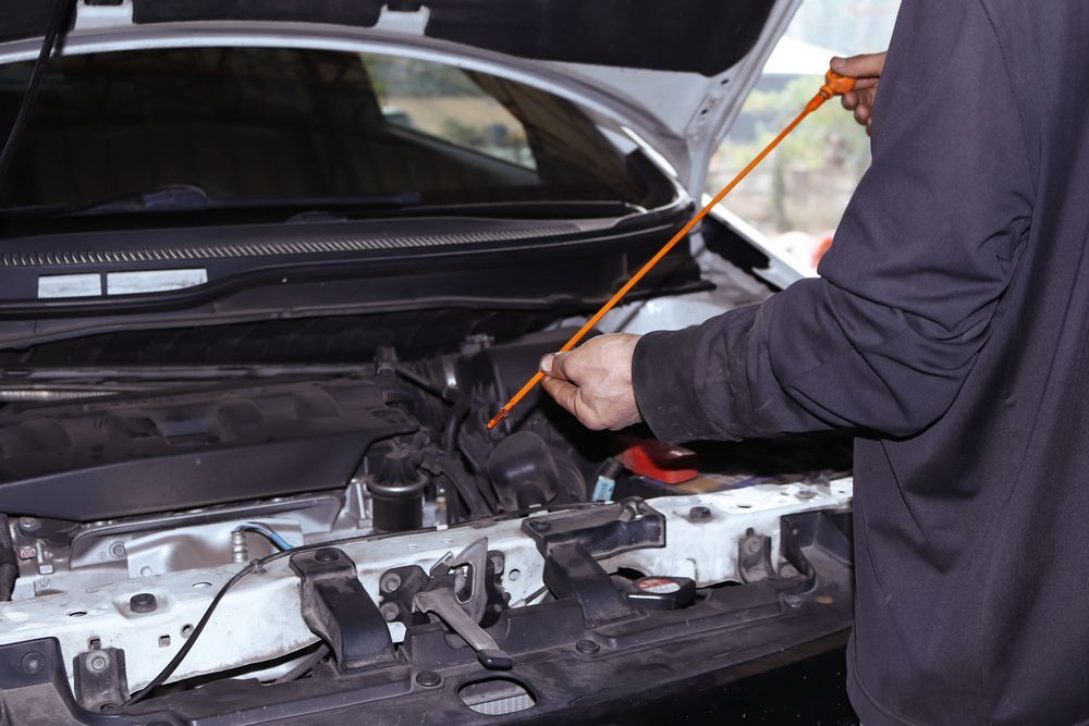 A Man is Checking the Oil in a Car With the Hood Open — Hive Mobile Roadworthy in Mount Nathan, QLD