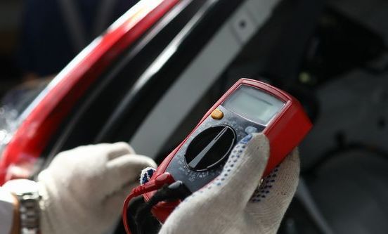 A Person is Holding a Red Multimeter in Their Hand — Hive Mobile Roadworthy in Pimpama, QLD