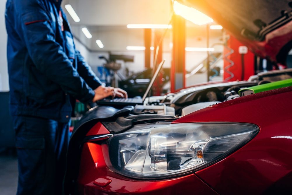 A Mechanic is Working on a Red Car in a Garage — Hive Mobile Roadworthy in Southport, QLD