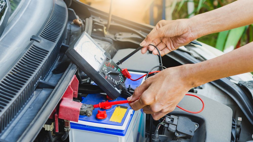 A Person is Working on a Car Battery With a Multimeter — Hive Mobile Roadworthy in Helensvale, QLD