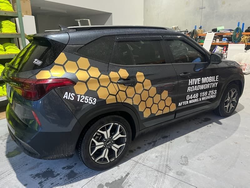 A Car With a Honeycomb Design on the Side is Parked Inside a Garage — Hive Mobile Roadworthy in Mount Nathan, QLD