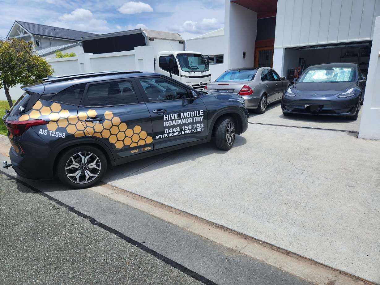 A Black Car With Honeycombs on the Side is Parked in Front of a Garage — Hive Mobile Roadworthy in Southport, QLD