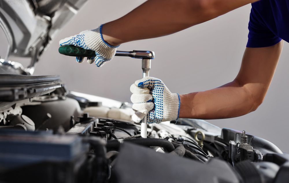 A Man is Working on the Engine of a Car With a Wrench — Hive Mobile Roadworthy in Robina, QLD