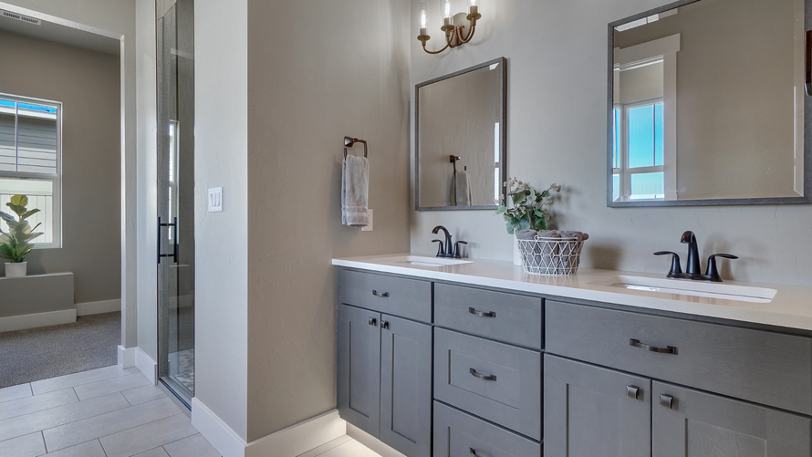 A bathroom with two sinks , two mirrors and a walk in shower.