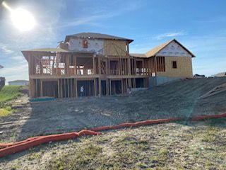 A large house is being built on top of a dirt hill.