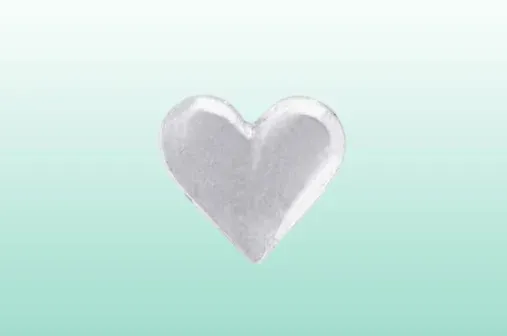 et lite sølvhjerte på en grønn bakgrunn.