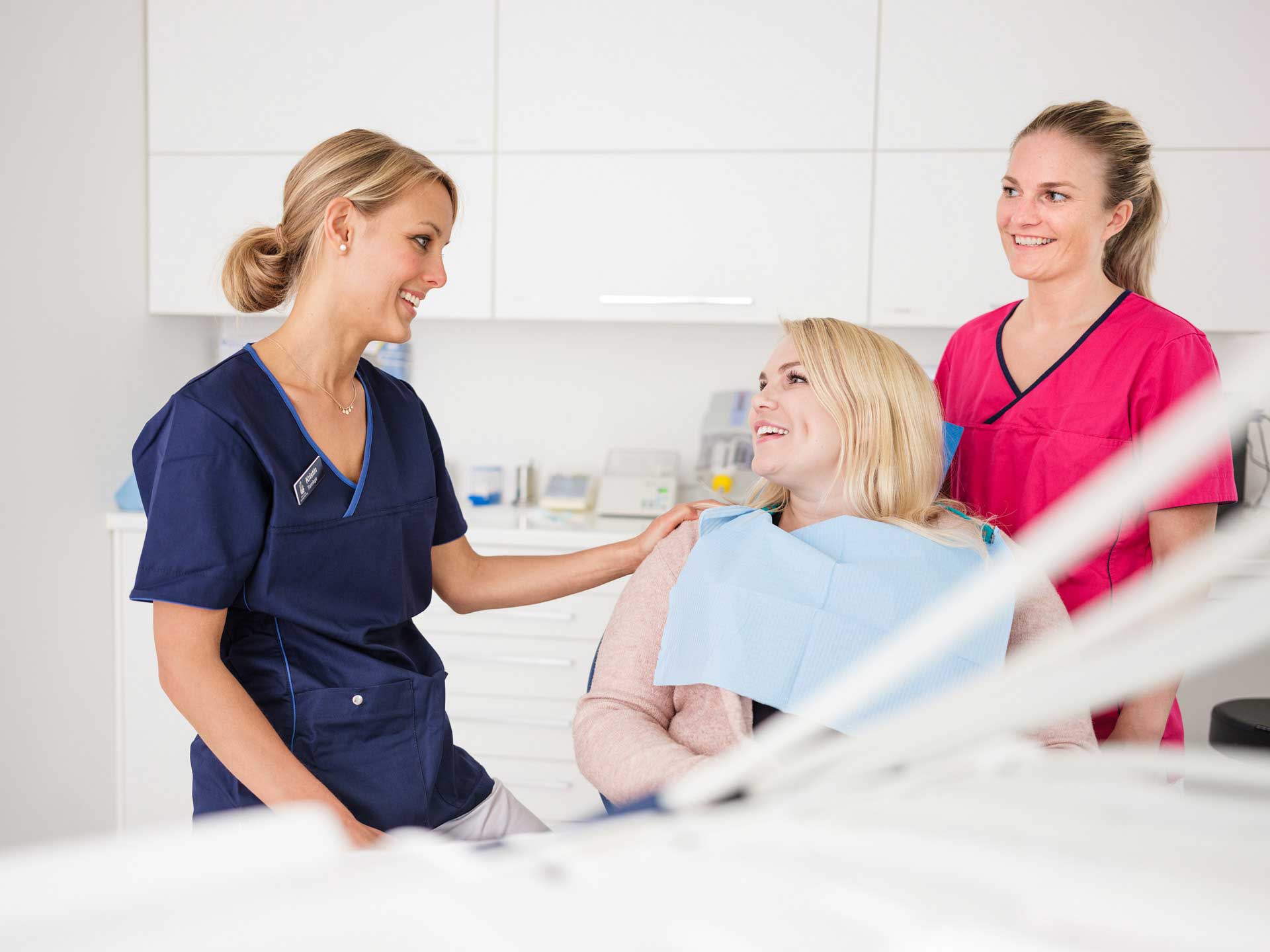 Bilde av en tannlege og en tannpleier sammen med en pasient som smiler