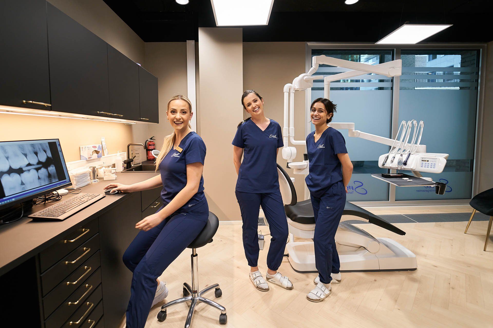 tre kvinnelige tannleger poserer på et tannlegekontor.