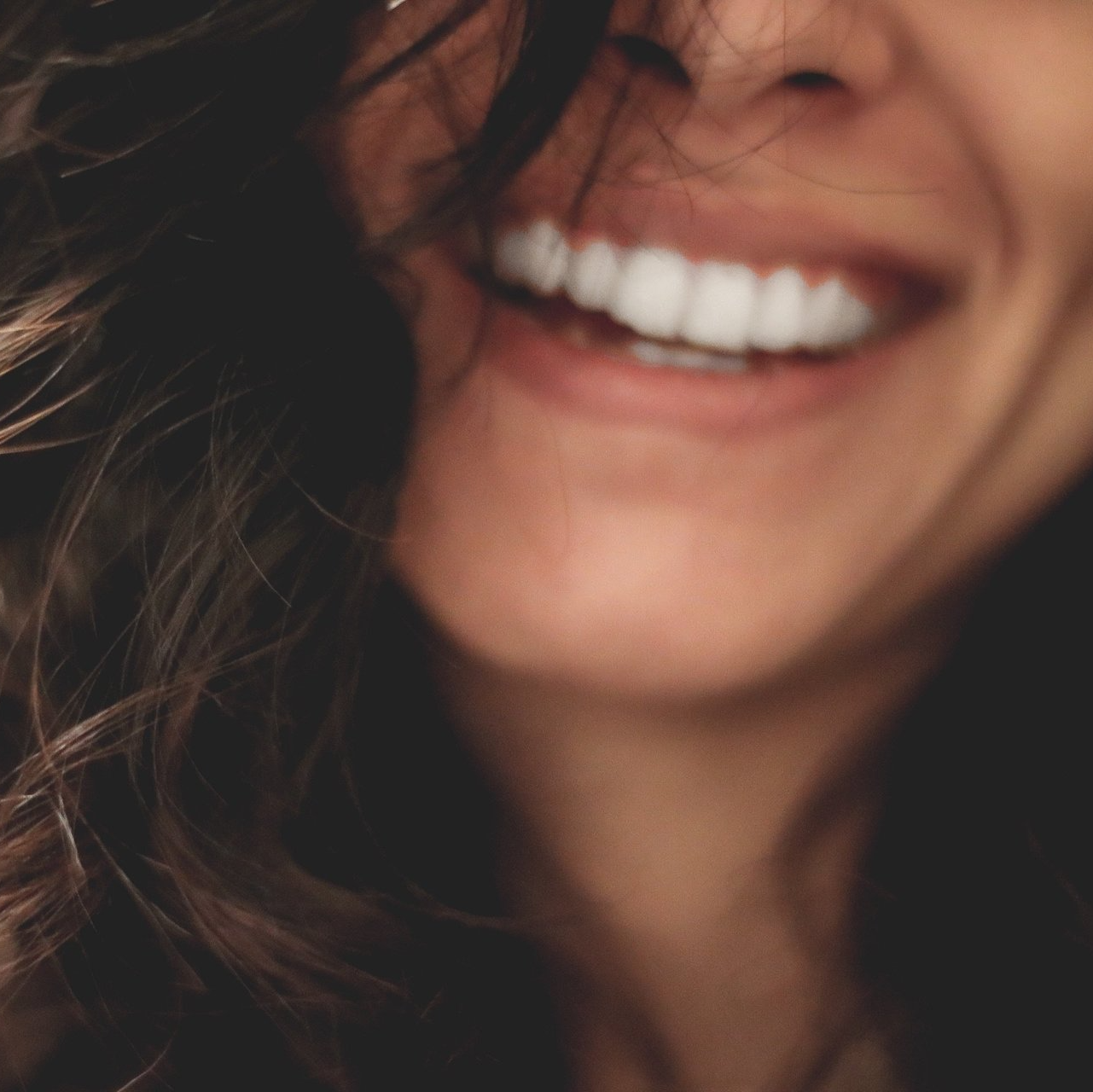 Kvinne som smiler bredt med hvite tenner