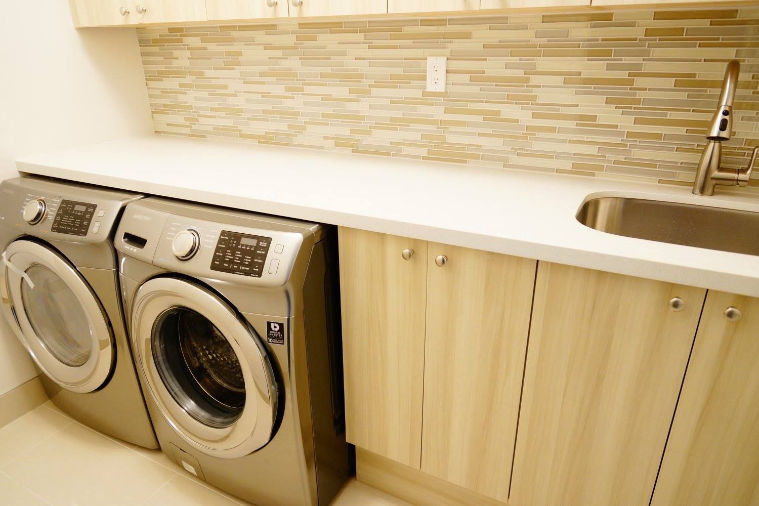 A laundry room with a washer and dryer and a sink