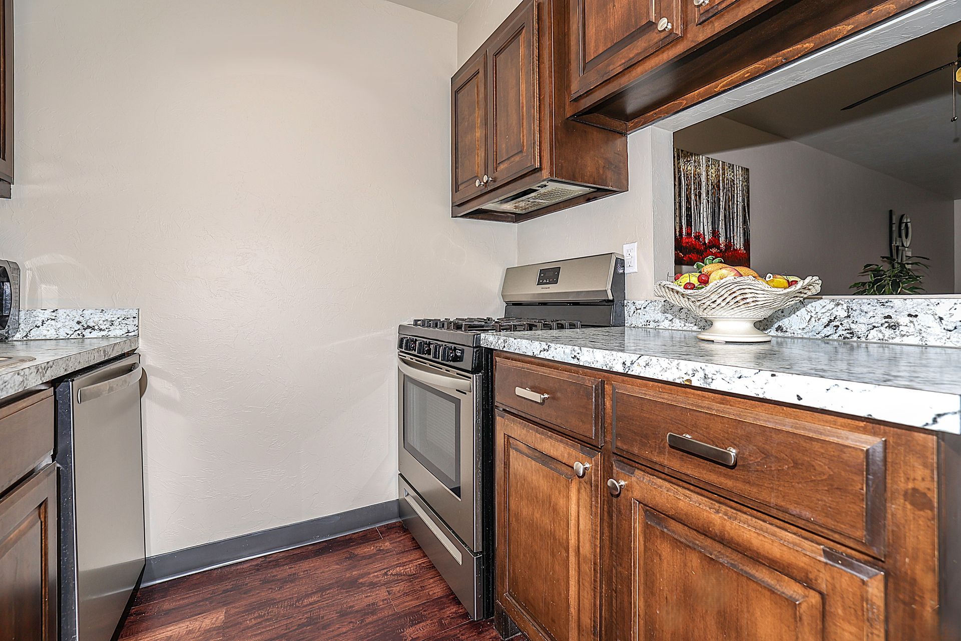 Kitchen with stainless steel oven, wood cabinets, granite countertops, and pass-through window.