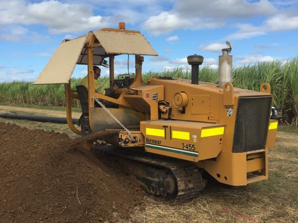A man is driving a yellow bulldozer in a field.
