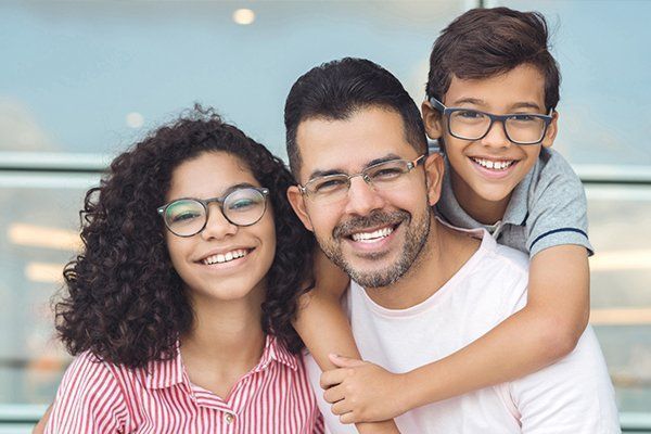 A man and two children wearing glasses are posing for a picture.