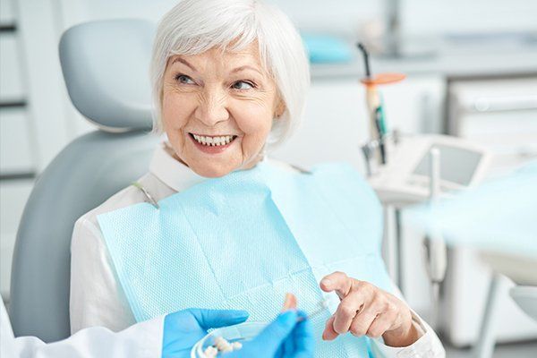 An elderly woman is smiling while sitting in a dental chair.
