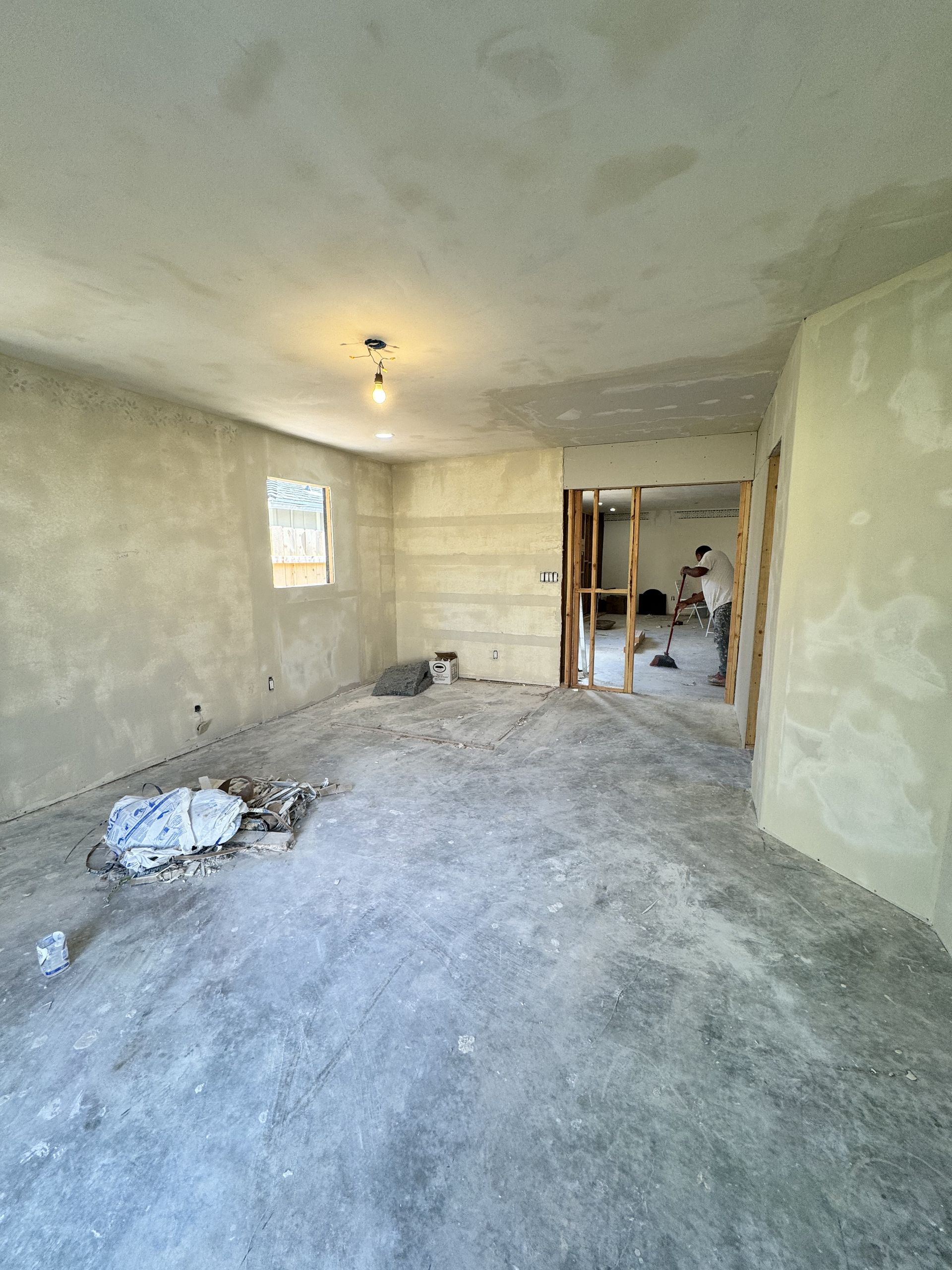 Renovated empty room with unfinished walls, bare floor, and ceiling light