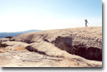 A person is standing on top of a rocky hill.