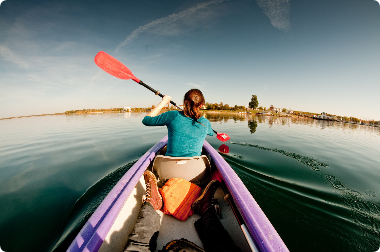 A woman is paddling a kayak on a lake.