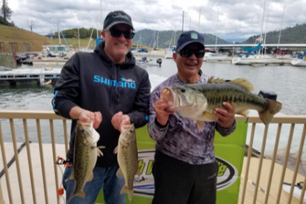 Two men are standing next to each other holding fish in their hands.