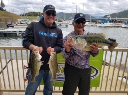 Two men are standing next to each other holding fish in their hands.
