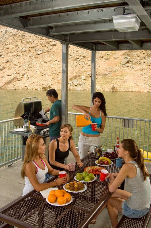 A group of people are sitting at a picnic table near a lake.