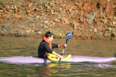 A man is paddling a kayak on a lake.