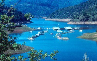 A lake with a lot of boats on it and mountains in the background.