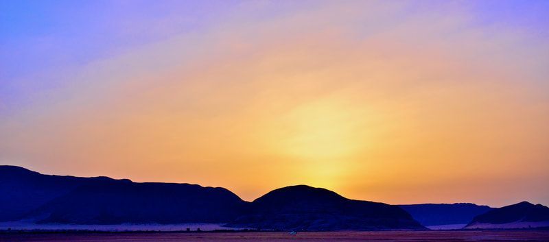 The sun is setting over the mountains in the desert.