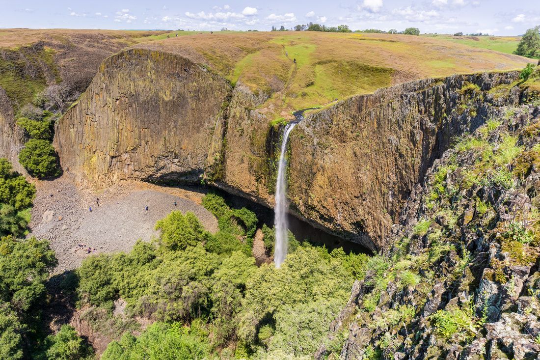 An aerial view of a waterfall surrounded by trees and rocks.
