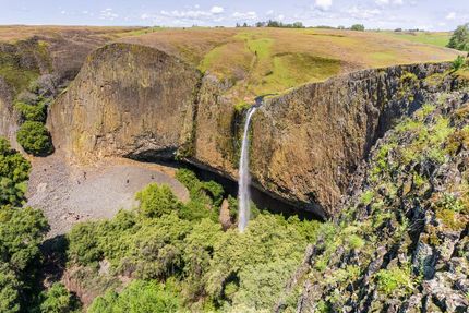 An aerial view of a waterfall surrounded by trees and rocks.