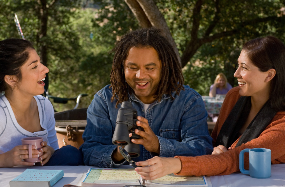 A group of people are sitting at a table looking through binoculars.